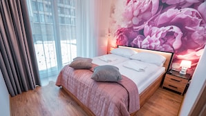 A hotel room with a bed, pillows, a nightstand, a lamp, and a window with curtains. - Apartamenty Sun & Snow Cicha (Krynica-Zdroj)