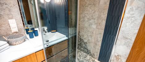 A modern bathroom with a glass-enclosed shower, a white sink, and a wooden vanity.
