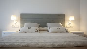 A neatly made bed with a patterned bedspread and two pillows, flanked by two bedside lamps on white nightstands.