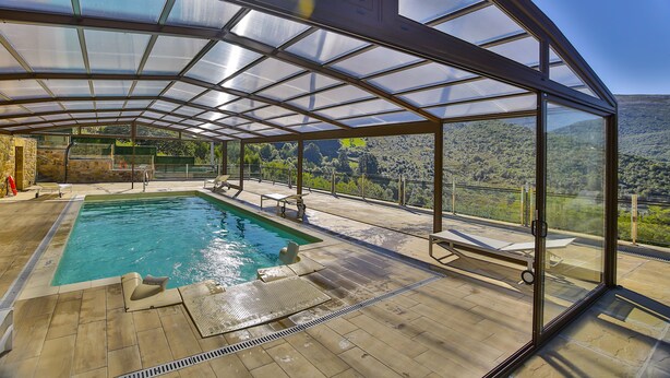 Un área de piscina con paredes de vidrio y vistas a un paisaje montañoso.