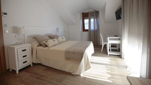 Un dormitorio con cama, mesita de noche, lámpara y escritorio con silla.