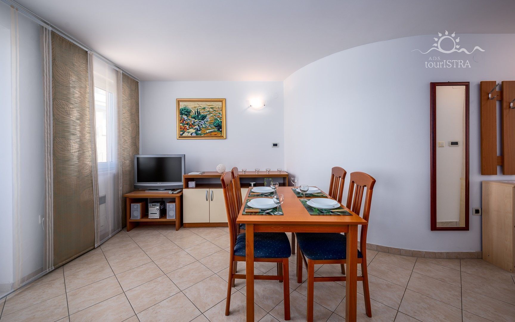 Un espacio habitable compacto con comedor, televisión y un cuadro en la pared.