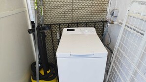 A compact laundry room with a white washing machine, a yellow vacuum cleaner, and a mop. - Feel Welcome Barcelona Splau (Cornella de Llobregat)