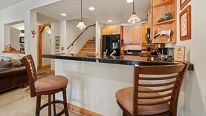 Una cocina moderna con armarios de madera, un refrigerador negro y una isla integrada con taburetes de bar.