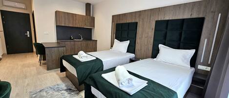 Habitación de hotel con dos camas, un escritorio y una kitchenette.