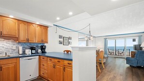 Eine moderne Küche mit Holzausstattung und einer blauen Arbeitsplatte, die zu einem Balkon mit Meerblick führt.