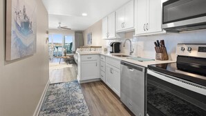 Una cocina moderna con armarios blancos, electrodomésticos de acero inoxidable y una alfombra azul.