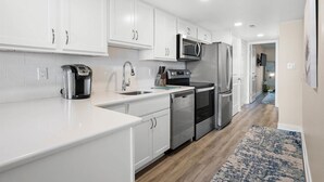 Una cocina moderna con armarios blancos, electrodomésticos de acero inoxidable y piso de madera.
