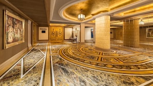 Un lobby lujoso con pisos de mármol, columnas ornamentadas y un gran candelabro.