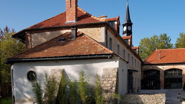 Un bâtiment historique doté d’un clocher, de murs en pierre et d’une pelouse bien entretenue, agrémentée de chemins en pierre.