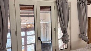 Une chambre à coucher avec un lit, des rideaux et une vue par la fenêtre.