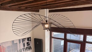 Un salon moderne avec un canapé en cuir noir, une table basse en bois et un luminaire au plafond au design original.