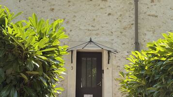 A building with a black door, a small porch, and potted plants.