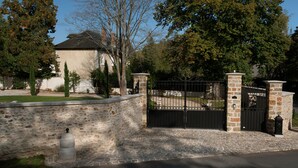 Une propriétéClose, entourée d’un mur en pierre et dotée d’une allée pavée menant à une maison au toit sombre.