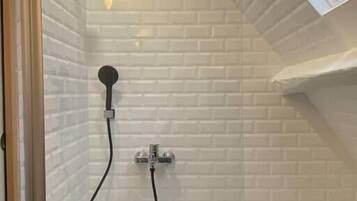 A modern shower with a glass enclosure, white tiled walls, and a skylight.