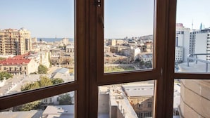 Une vue depuis une fenêtre donnant sur un paysage urbain, avec différents bâtiments et une tour au loin.
