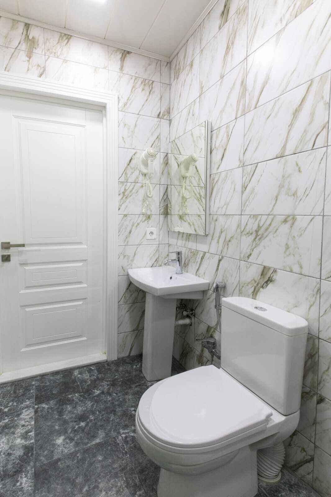 A bathroom with a white toilet, a pedestal sink, and a white door.