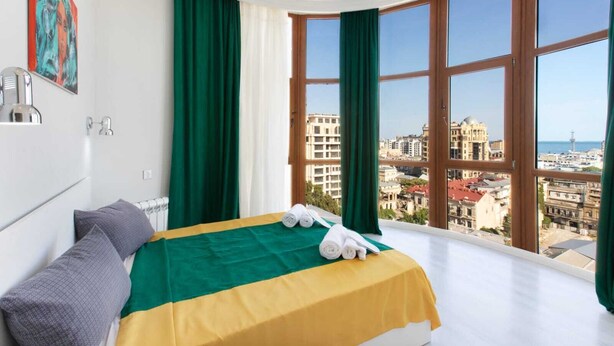 Une chambre d’hôtel avec un lit, une vue sur la ville et un tableau au mur.