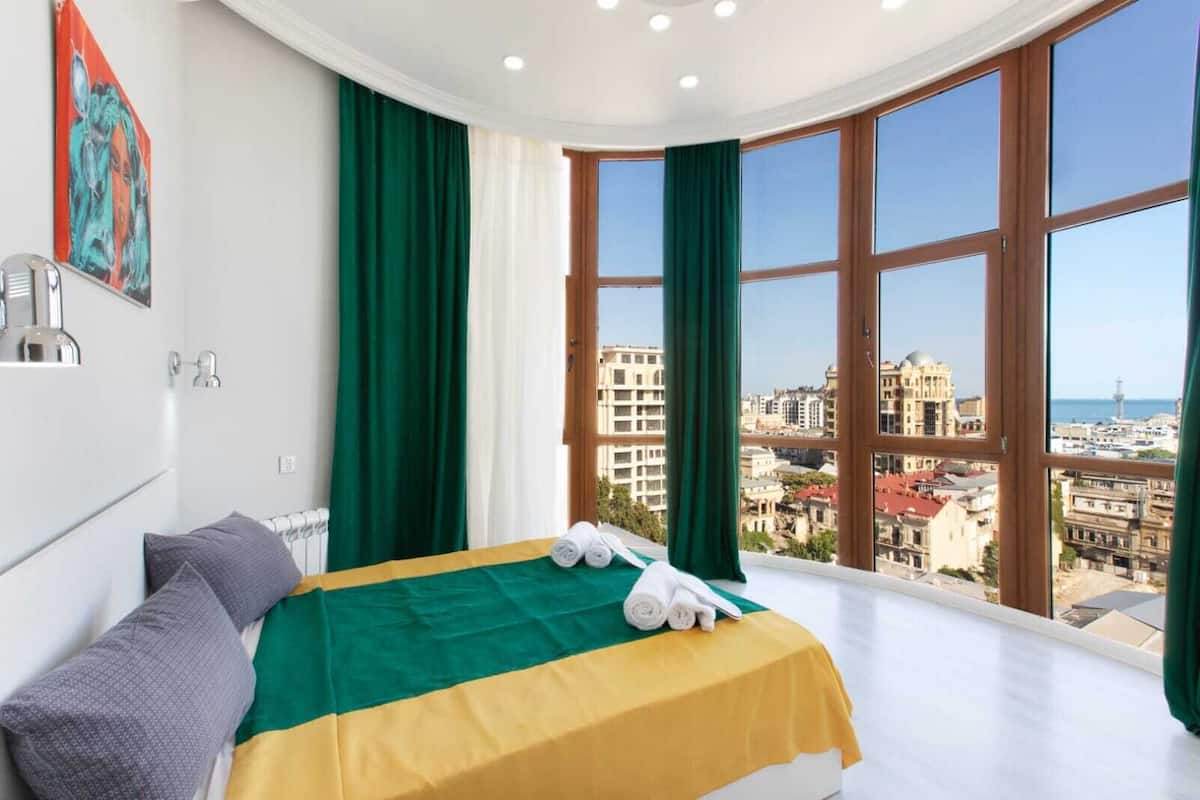 Ein Hotelzimmer mit Bett, Blick auf die Stadt und einem Gemälde an der Wand.