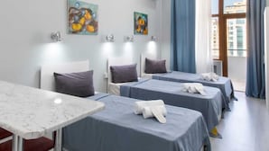 Une chambre d’hôtel avec quatre lits, une table en marbre et des œuvres d’art accrochées aux murs.