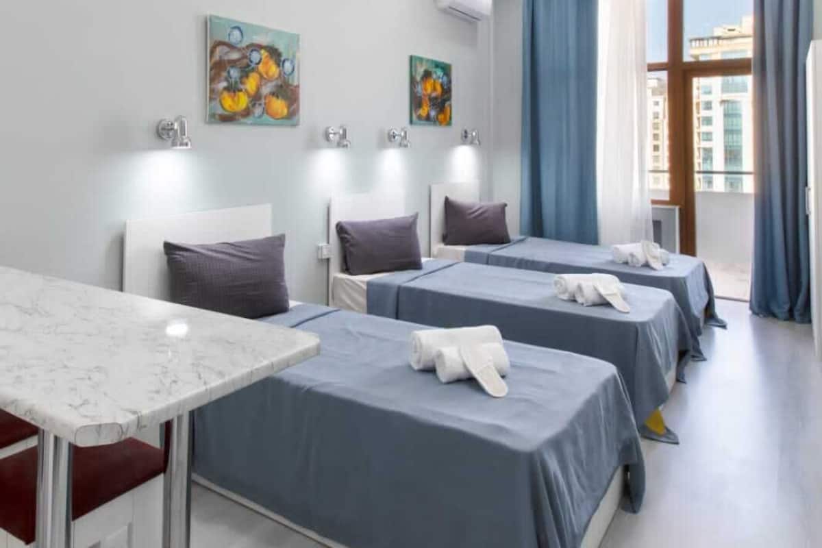 Ein Hotelzimmer mit vier Betten, einem Marmortisch und Bildern an den Wänden.