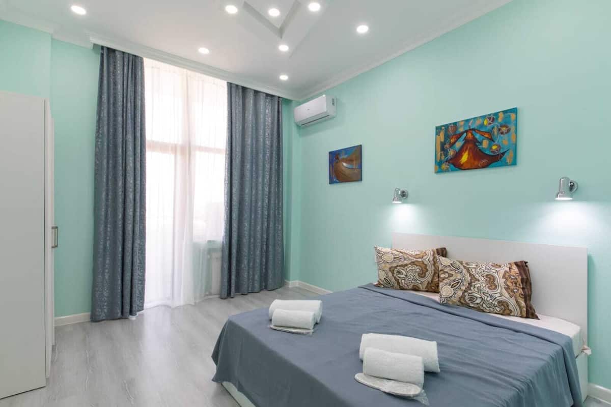 Ein Schlafzimmer mit Bett, Vorhängen, einem Gemälde und einer Klimaanlage.