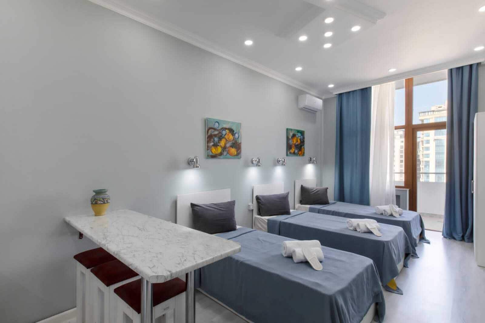 Una habitación de hotel con tres camas, una mesa de comedor y obras de arte en las paredes.