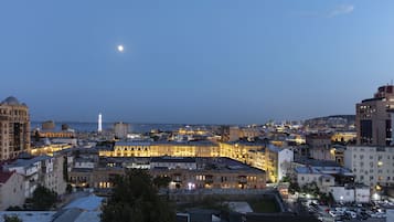 A cityscape at dusk with illuminated buildings and a prominent tower in the background.