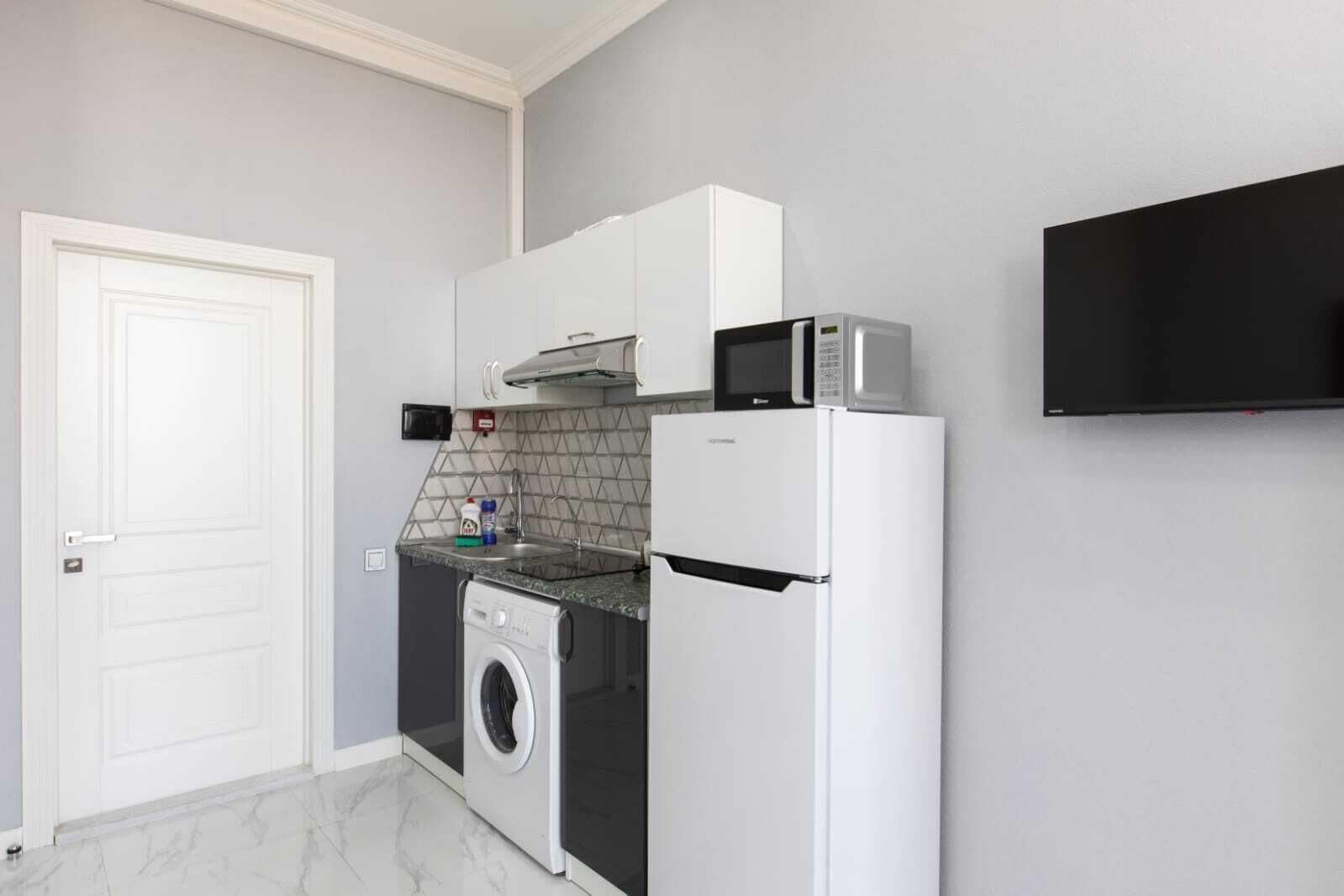 Une cuisine compacte équipée d’un lave-linge, d’un four à micro-ondes et d’un réfrigérateur.