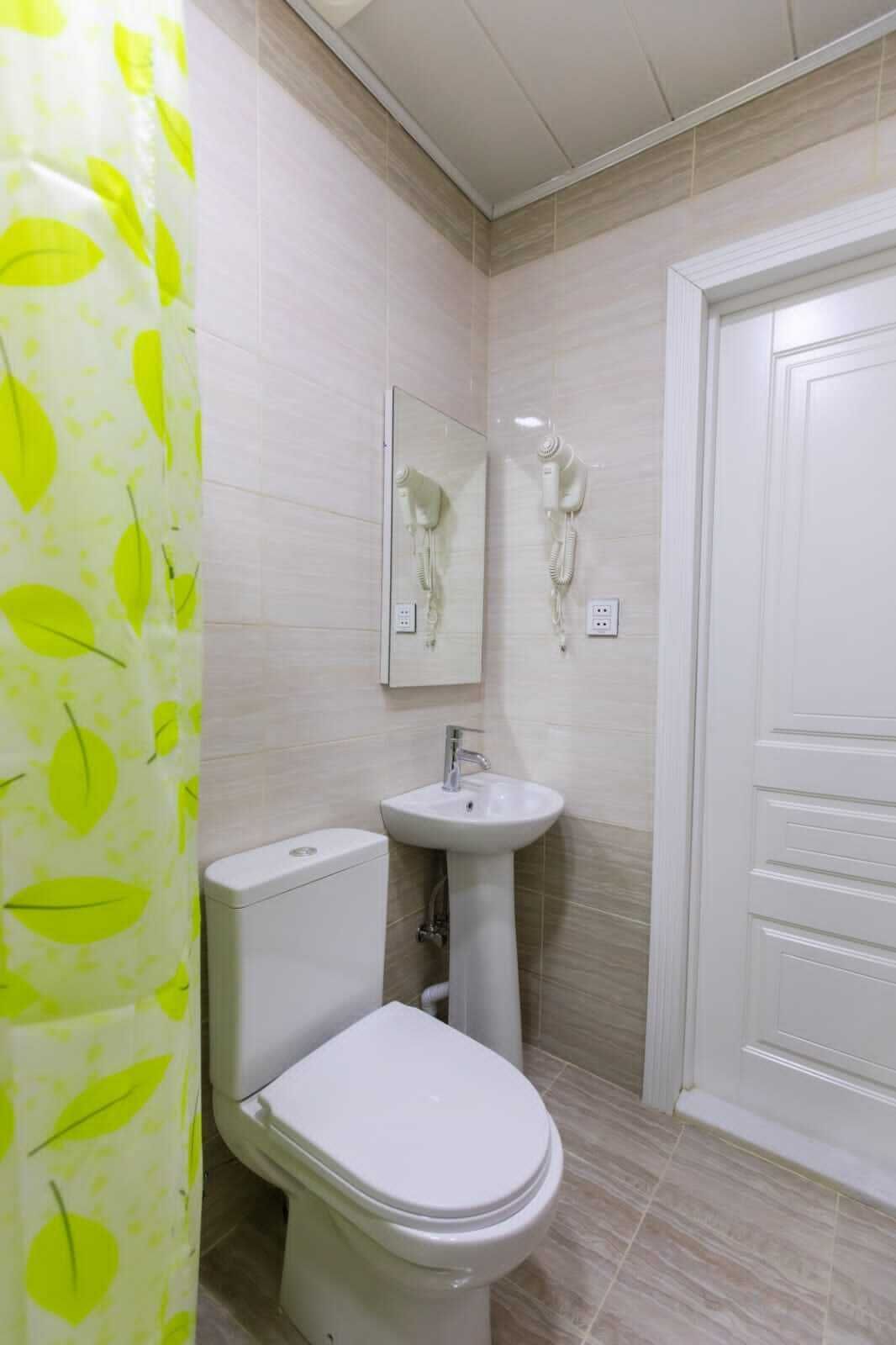A bathroom with a toilet, sink, and a hairdryer mounted on the wall.