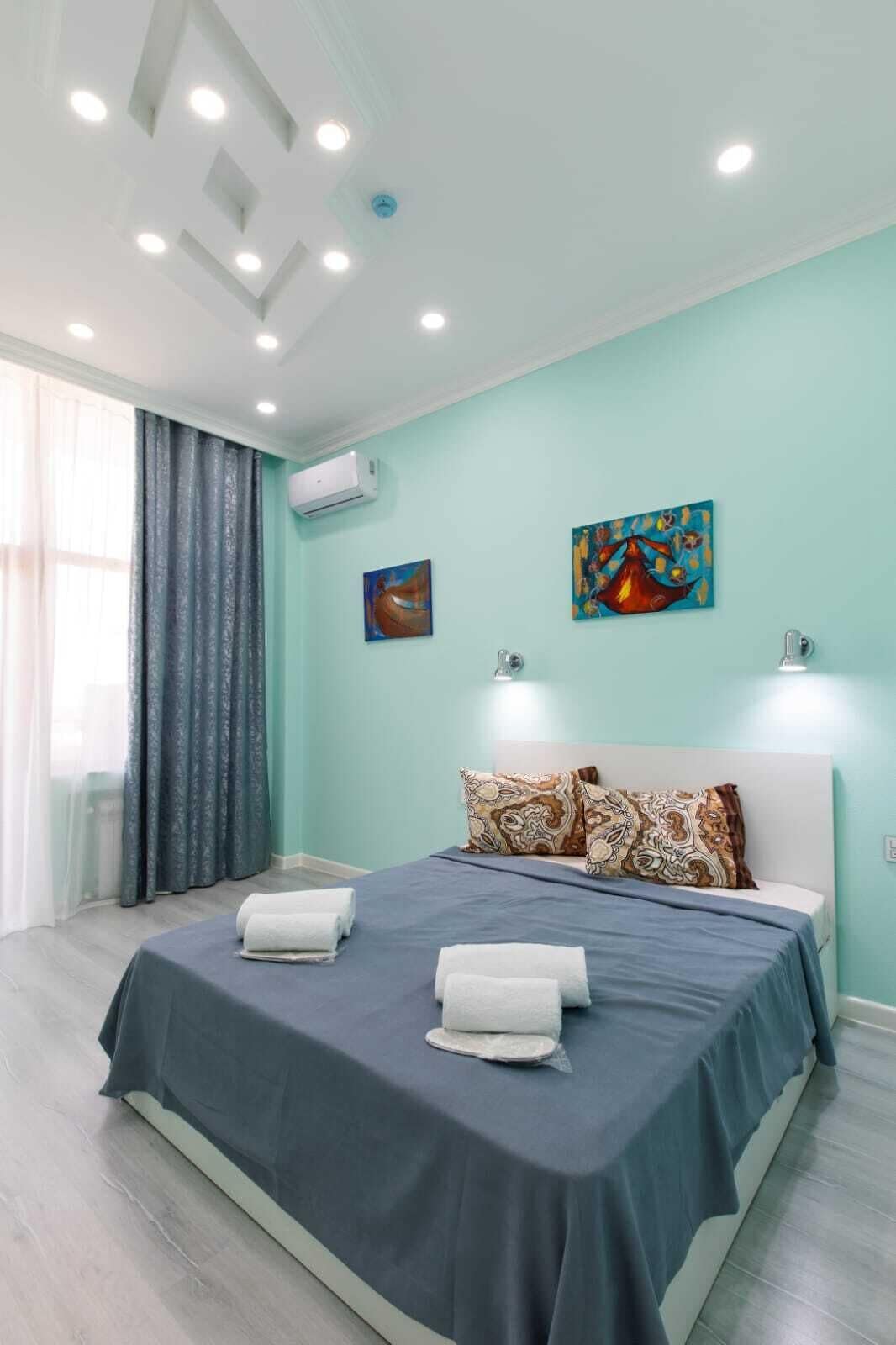 Un dormitorio moderno con una cama grande, dos luces fijadas a la pared y dos cuadros.