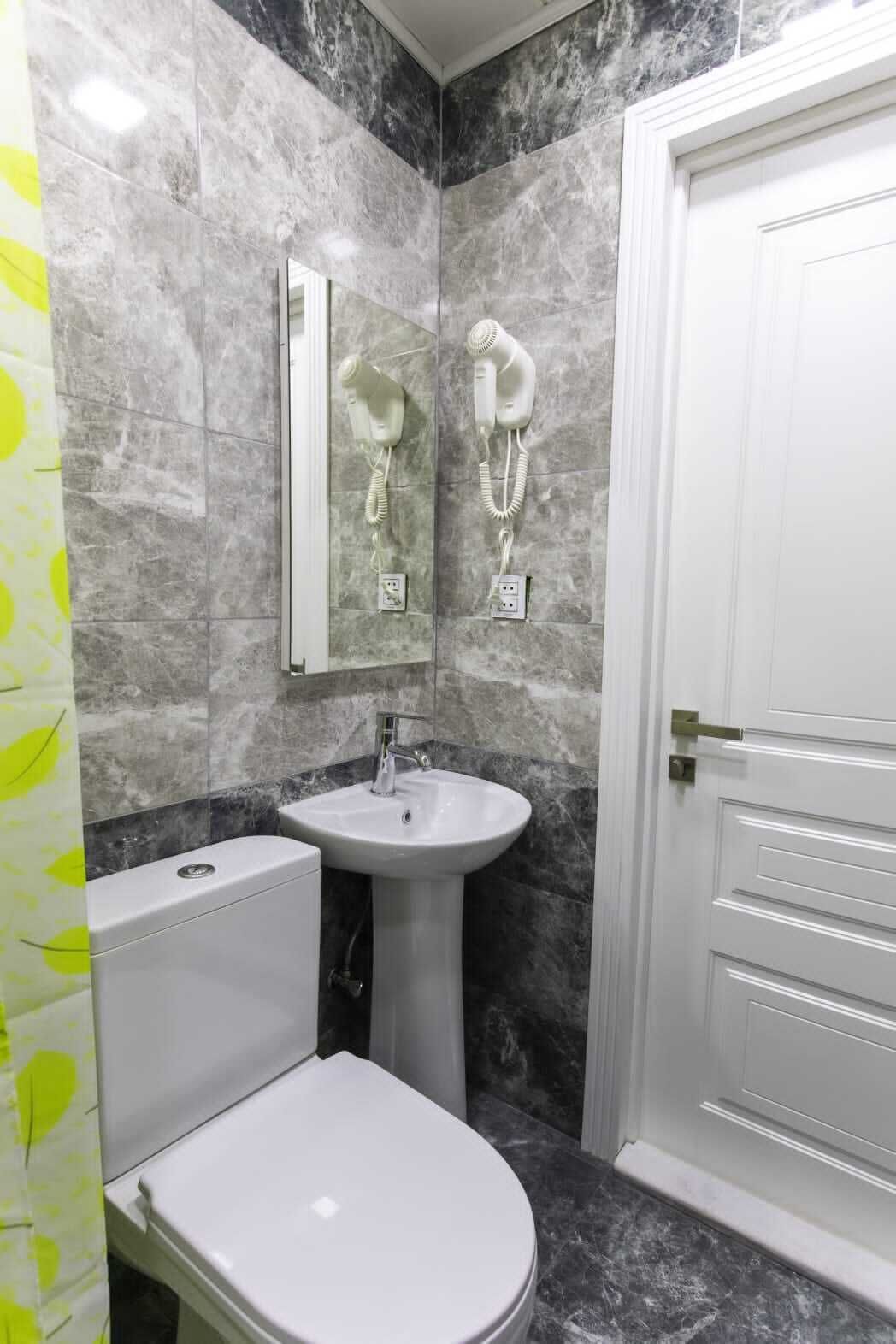 Een badkamer met toilet, wastafel en een haardroger bevestigd aan de muur.