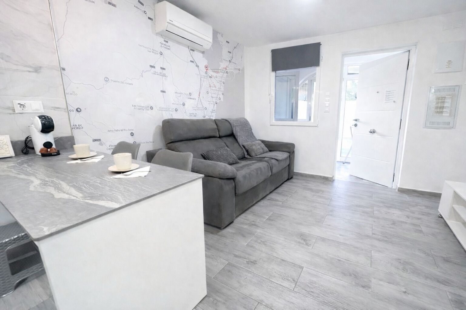 Ein modernes Wohnzimmer mit grauem Sofa, einem Couchtisch und einer Karte an der Wand.