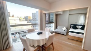 Una moderna camera d'hotel con un balcone, un'area pranzo con tavolo e sedie, e un letto a baldacchino.