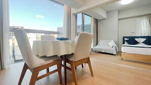 Una camera d'albergo moderna con balcone, angolo ristoro con tavolo e sedie, e un letto con testiera.