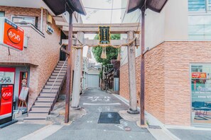 A narrow alleyway with a staircase leading to a building. There are signs and a banner hanging from the structure. - Shinkou House UE (Osaka)