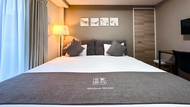 Una camera d'albergo con un letto, una lampada da comodino, una TV e opere d'arte appese al muro.