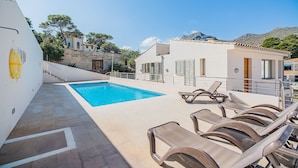 A pool area with lounge chairs, a clear blue pool, and a white building with a tiled roof. - Can Botana Casa 8 - By Dream Villas Pollensa (Cala San Vicente)