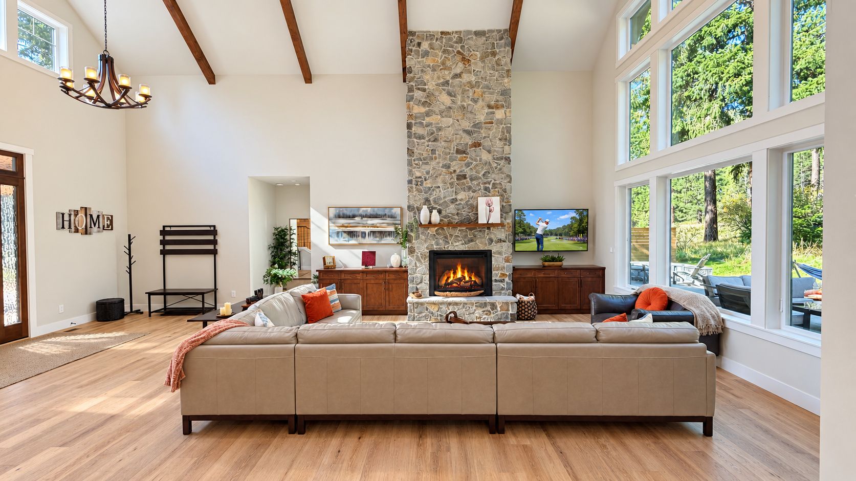 A spacious living room with a stone fireplace, a large sectional sofa, and a television.