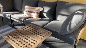 A gray sofa with a striped pillow and a woven coffee table. - Charming artist’s cottage near the beach, large lot with beautiful oaks (Oak Island)
