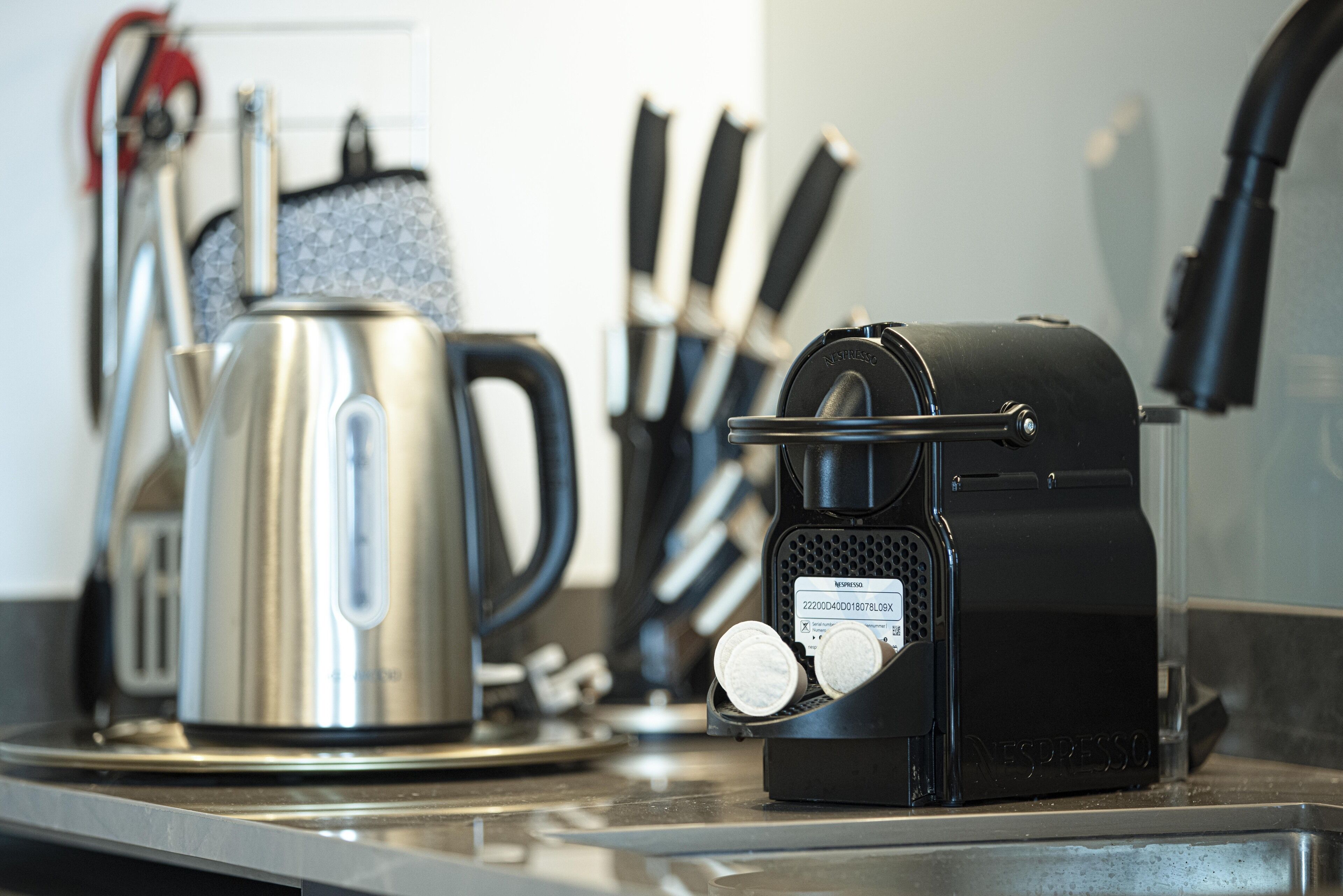 A coffee machine, a kettle, and a knife set on a kitchen counter.