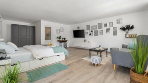 Ein modernes, helles Wohnzimmer mit einer Couch, einem Esstisch und einem an der Wand befestigten Fernseher.