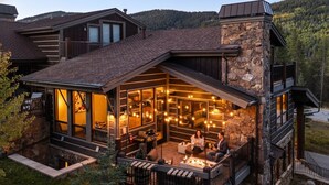 Una casa moderna con fachada de piedra, ventanas amplias y una terraza con mobiliario exterior.