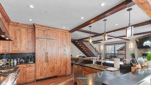 Una cocina amplia con armarios de madera, una isla grande, electrodomésticos de acero inoxidable y vistas al exterior.