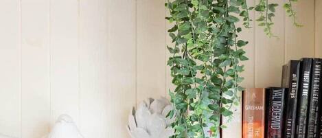 A bookshelf with books, a white vase, and a hanging plant.