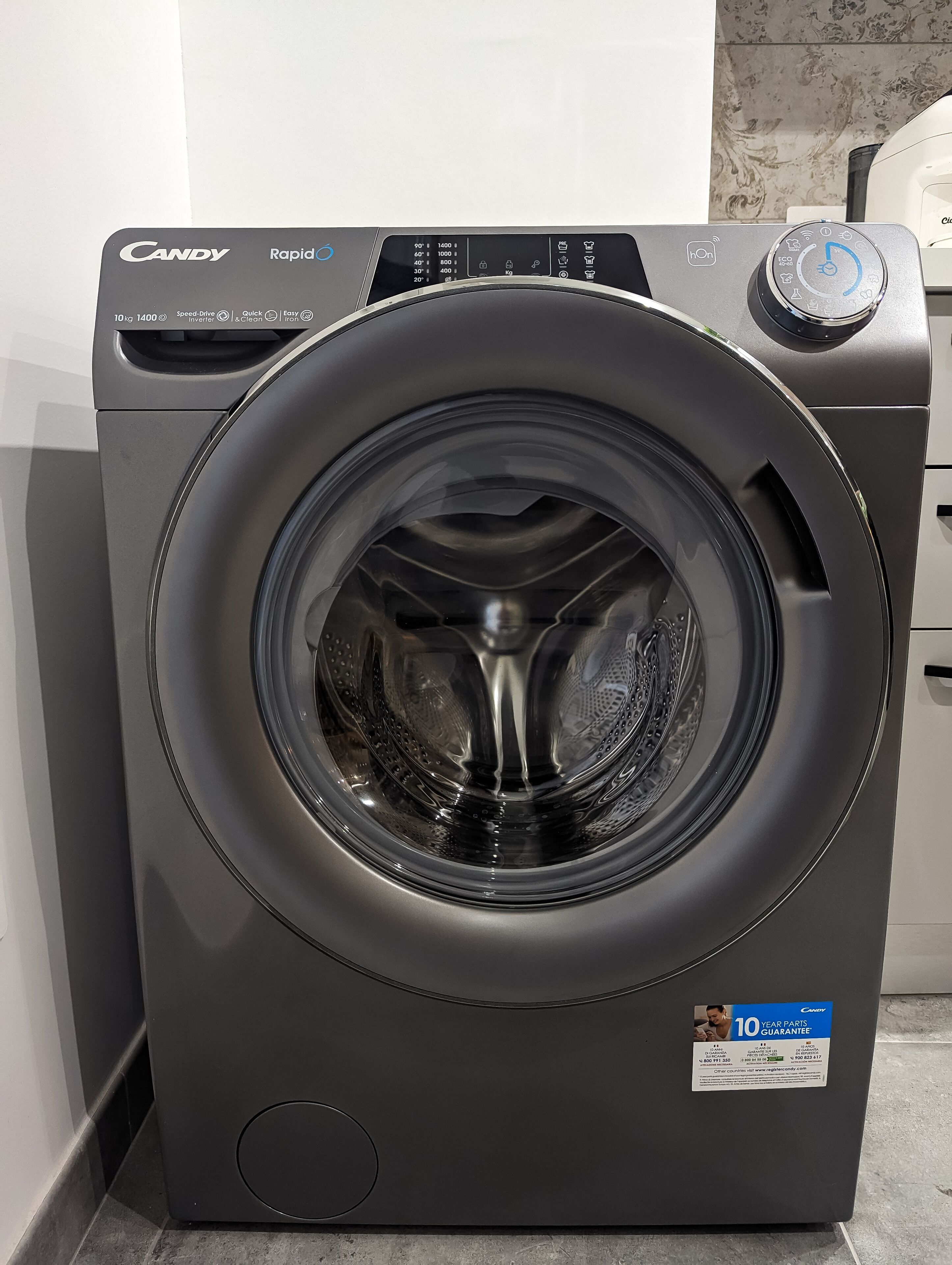 A front view of a Candy Rapid washing machine with a digital display, control panel, and a 10-year parts guarantee sticker.