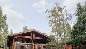 A rustic wooden cabin with a porch, surrounded by lush greenery and trees. - 10 Water's Edge (Morpeth)