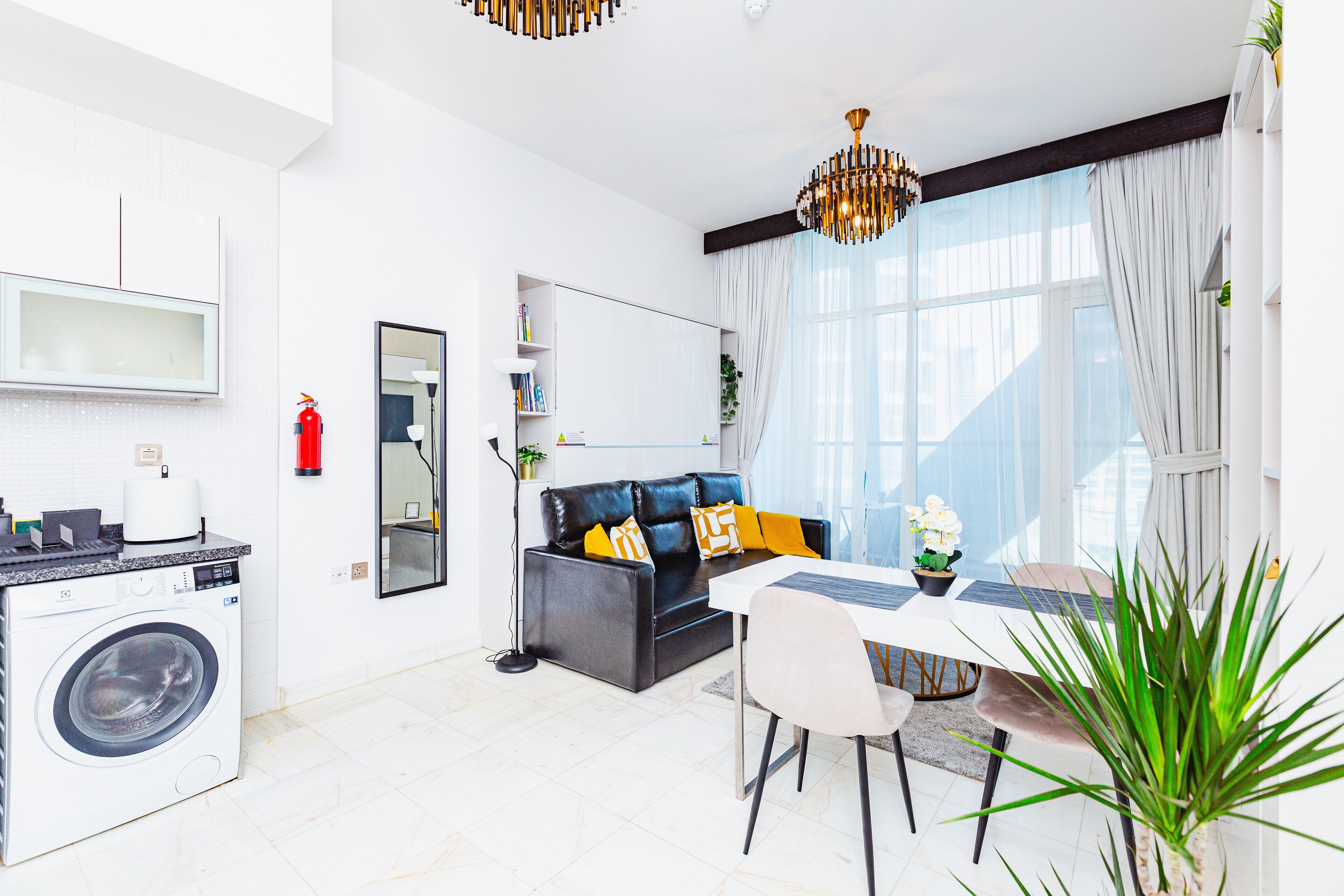 A modern living room with a sofa, dining table, and a washing machine.