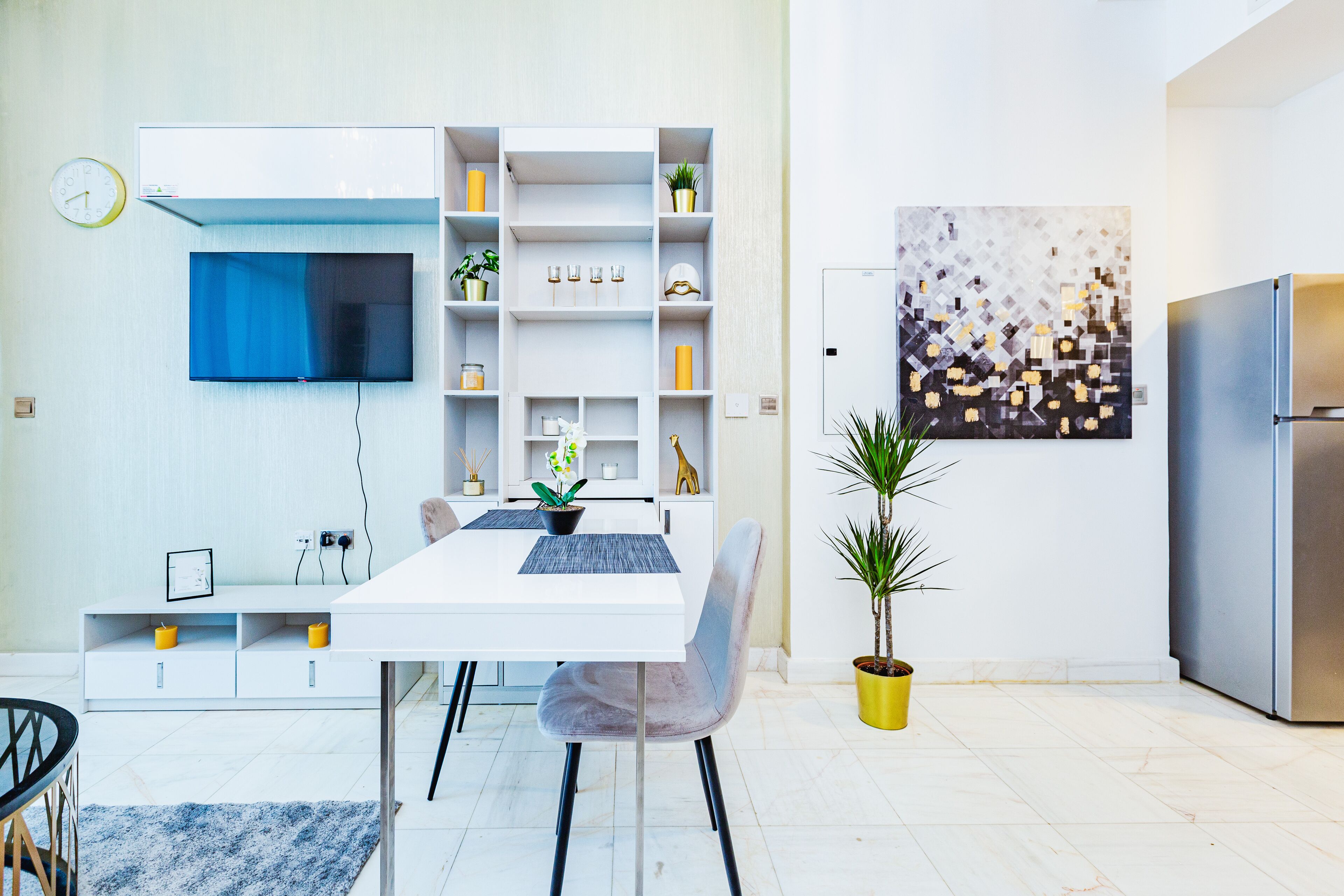 A modern kitchen with a built-in TV, white cabinetry, and a dining area with a table and chairs.