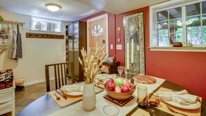 A dining area with a table set for four, a vase with dried flowers, and a window with autumn leaves. - Lovely Salt Lake City Cottage w/ Outdoor Space! (Salt Lake City)